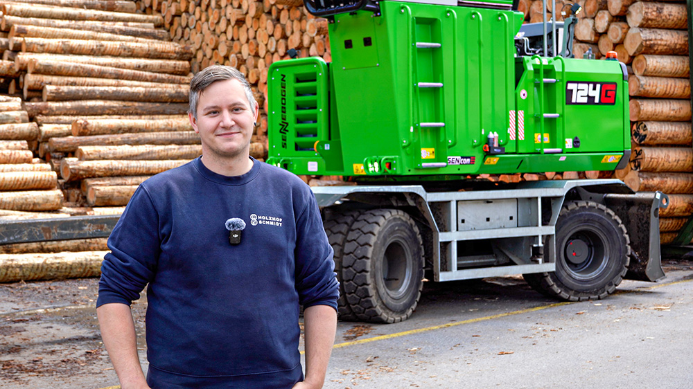 Holzfachmann mit grünem Sennebogen-Kran auf einem Sägewerksgelände in Österreich